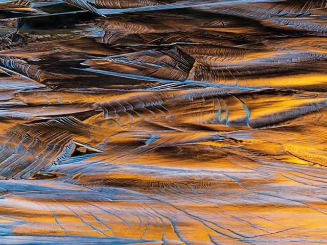 auf einer bergigen Landschaft schimmern Eisfelder in goldenem Licht.