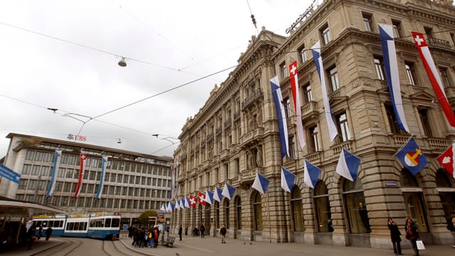 Der Paradeplatz in Zürich mit beiden Banken, UBS und CS, und einer Tramhaltestelle davor.