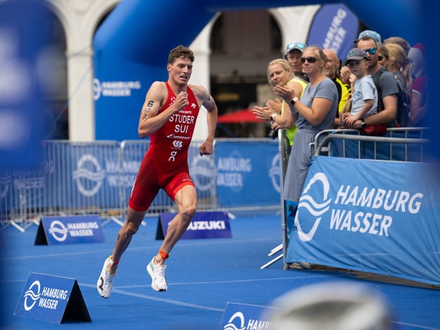 Triathlet beim Laufen während des Hamburg Wasser Triathlons, umgeben von jubelnden Zuschauern.