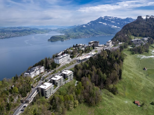 Luftaufnahme eines Resorts auf einem Hügel mit einem See und Bergen im Hintergrund.