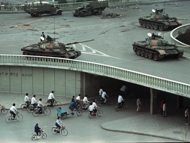 Panzer auf einer Brücke. Darunter Velofahrer