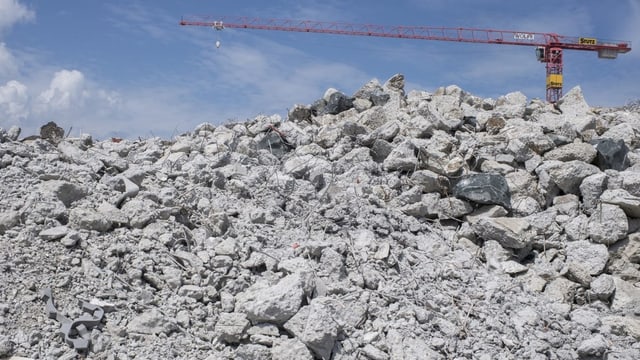 Ein Kran steht in der Ferne, davor eine Baustelle mit Steinen auf dem Boden.