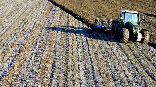 Ein Bauer pflügt mit einem Traktor ein Feld.