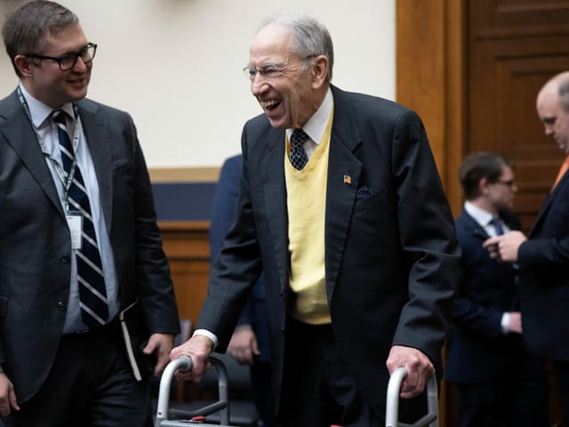 Der Senator geht an einem Rollator und lächelt herzhaft.