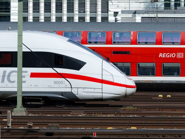 Ein ICE-Schnellzug steht auf einem Gleisfeld neben einem DB-Regionalzug.