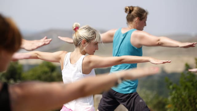 Drei Frauen praktizieren Yoga.