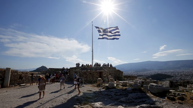 Touristen unter einer griechischen Flagge