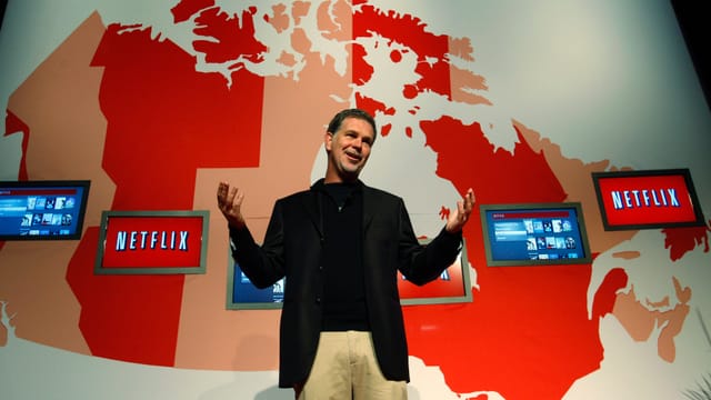 Netflix-CEO Reed Hastings steht vor einer Karte der USA.