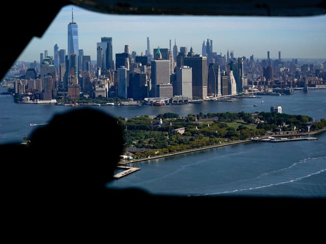 Skyline von Manhattan und Governors Island aus einem Flugzeugfenster.