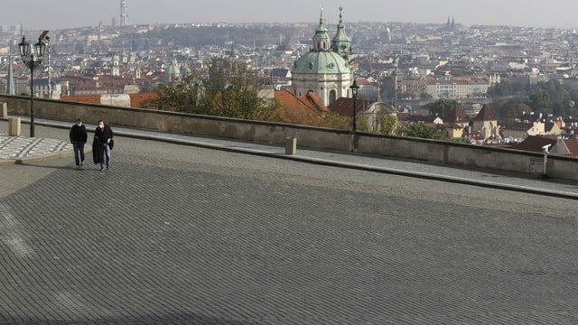 The squares are empty: two people run through the otherwise crowded square in front of Prague Castle.