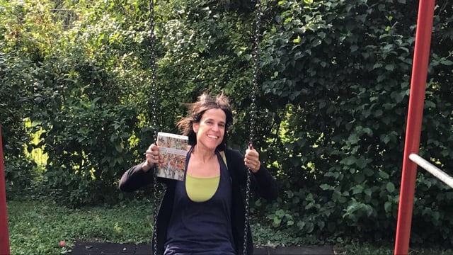 Annette König sitzt auf einer Schaukel, schwingt und hält das Buch «Liebe wird überschätzt» in der Hand