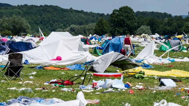 Wiese mit zerstören Zelten und haufenweise Abfall.