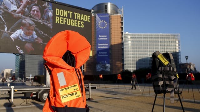 Eine Schwimmweste steht vor einem Plakat mit der Aufschrift «don't trade refugees» in Brüssel.