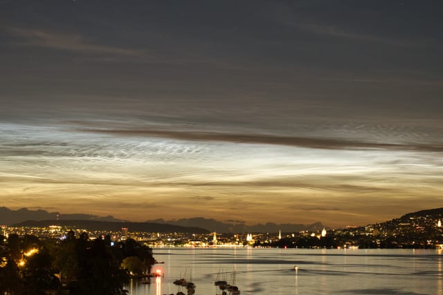 Silbern leuchtende Nachtwolken am dunklen Himmel.