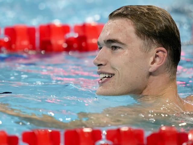 Mann im Schwimmbecken mit roten Bojen.