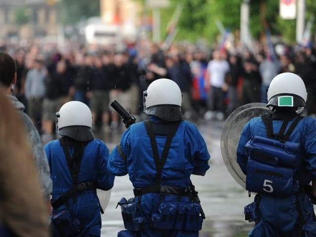 Polizistinnen in Vollmontur, im Hintergrund Fussballdfans.