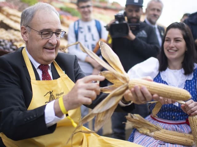 Bundespräsident Guy Parmelin hält einen Maiskolben in der Hand.