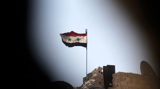 Eine syrische Flagge über flattert auf einem von Regierungstruppen kontrollierten Gebäude in Aleppo. 