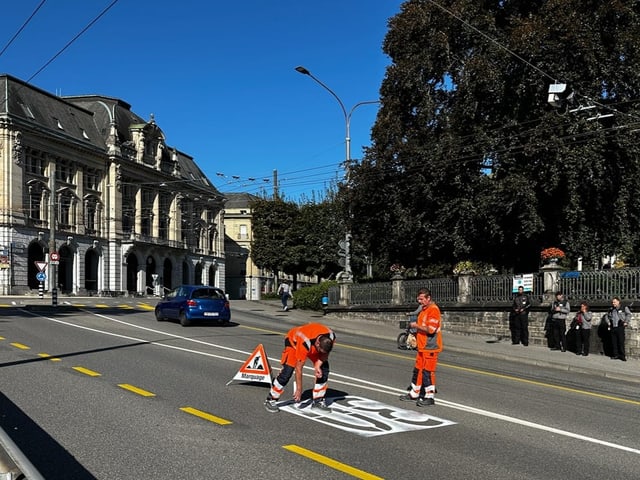 Zwei Bauarbeiter bemalen die Strasse mit einer 30.