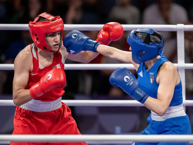 Zwei Boxer im Kampf, einer in roter Ausrüstung, der andere in blauer.