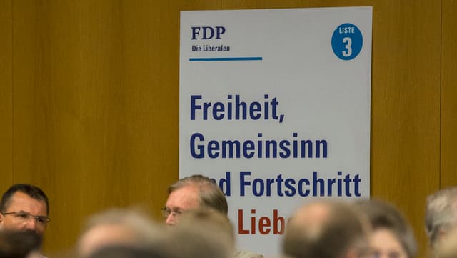 An einer Wand hängt ein Wahlplakat der FDP