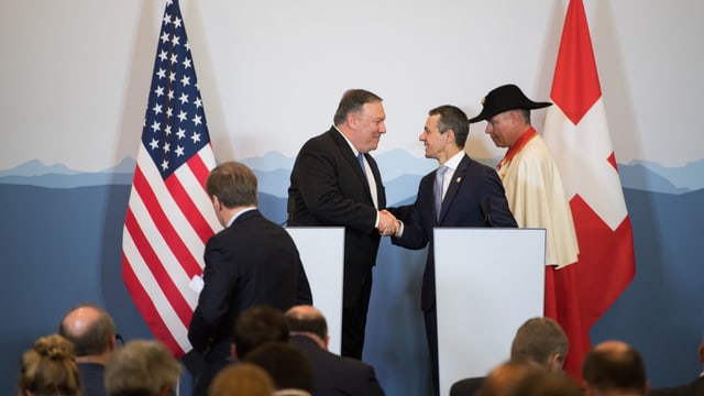 Pompeo und Cassis schütteln sich auf einer Bühne die Hände.