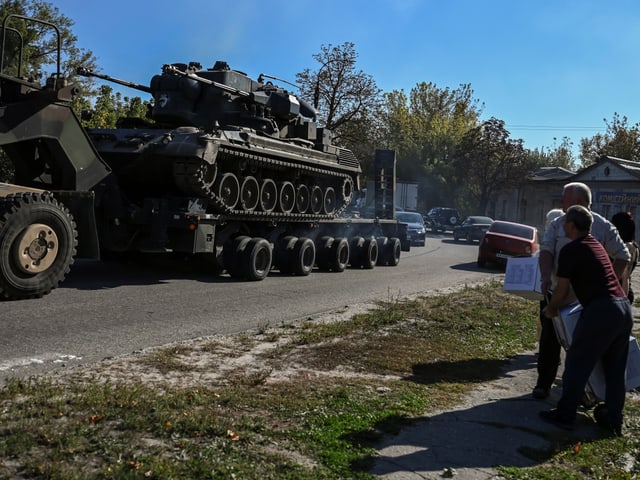 Ein Sattelschlepper fährt auf einer Strasse. Er hat einen Flugabwehrpanzer geladen.