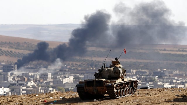 Ein türkischer Panzer auf einer Anhöhe nahe der Grenzstadt Kobane, wo Rauch aufsteigt.