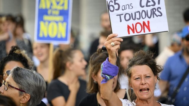 Menschen schwenken Plakate bei einer Demonstration gegen AHV 21 und gegen die Erhöhung der Mehrwertsteuer