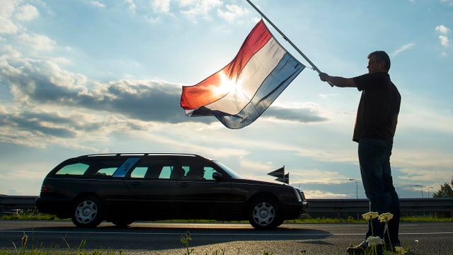 Ein Niederländer steht mit einer Flagge auf Halbmast, während Opfer des Flugzeugabsturzes vom Flughafen Nieuwegein in die Gerichtsmedizin transportiert werden. (reuters)