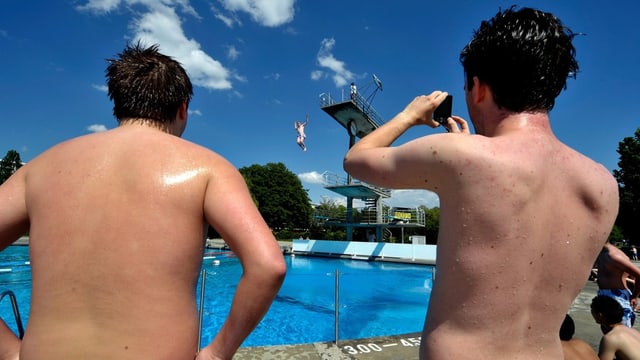 ZWei Jungs forografieren in der Badi jemanden, der vom Turm springt.