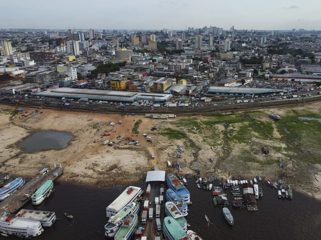 Luftaufnahme von Manaus mit Fluss und Booten im Vordergrund.