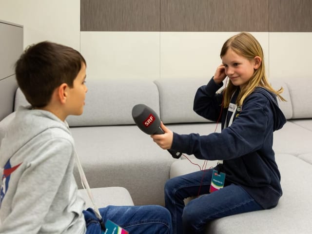 Redaktor erklärt Kindern eine Kamera