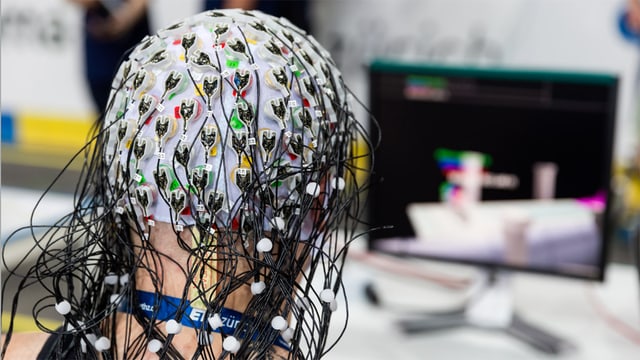 Ein Mann trägt ein mit Dutzenden von Sensoren bestücktes Brain-Computer-Interface.