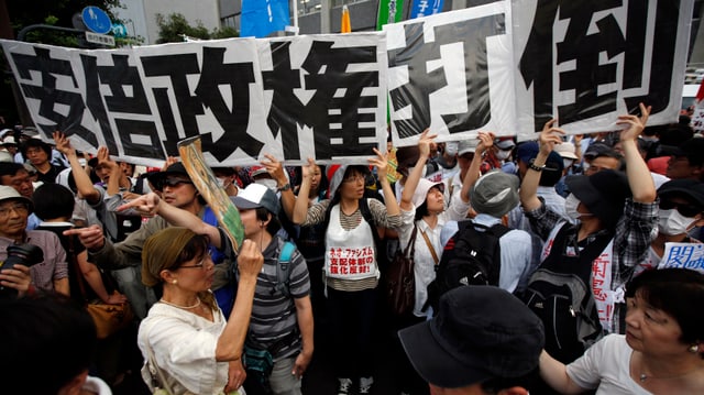 Japanische Demonstranten halten ein überlanges Transparent in die Höhe.