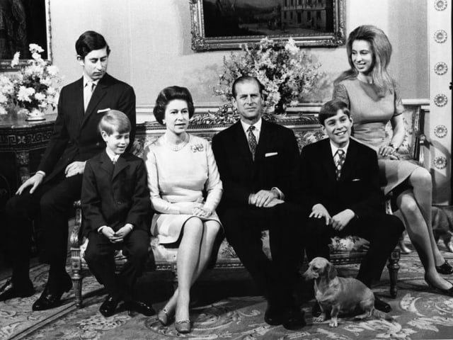 Black and white family portrait with parents and four children, plus a dachshund.