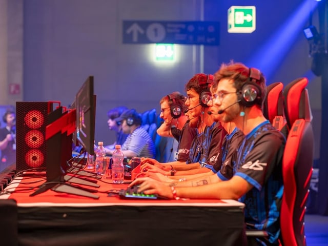 Mehrere Personen beim E-Sport-Wettbewerb mit Computern.