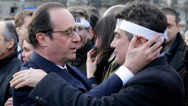 Hollande umarmt einen Mann mit weissem Stirnband