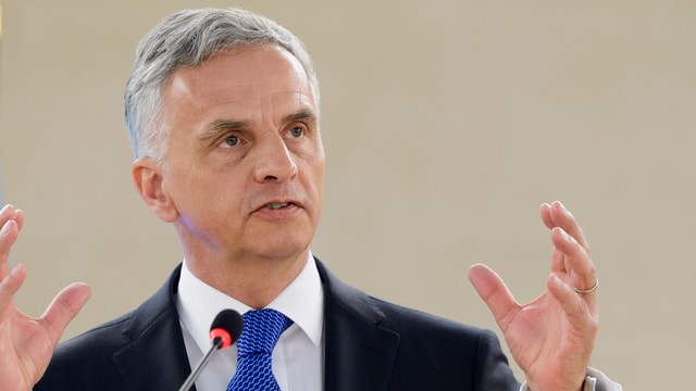 Burkhalter an einem Mikrofon, gestikulierend