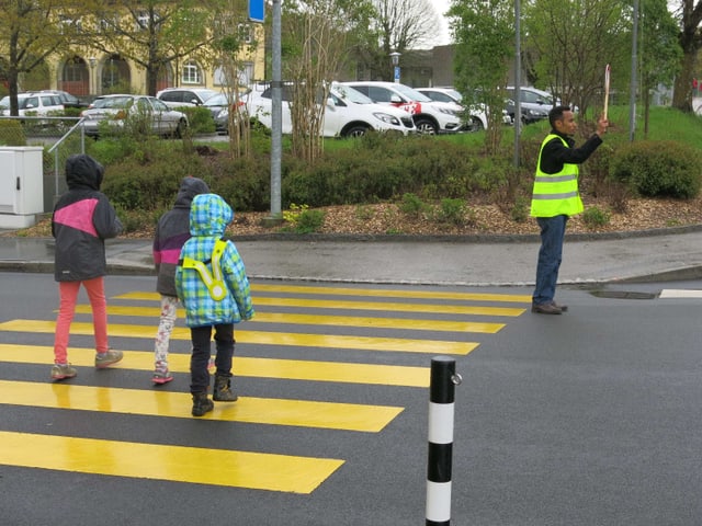 Kinder auf Fussgängerstreifen, Asylbewerber stoppt den Verkehr.