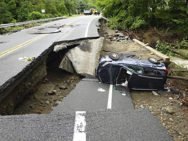 Ein Auto liegt umgekippt neben einer zerstörten Strasse im Hudson Valley.