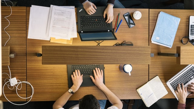 Vogelperspektive: Menschen arbeiten an Laptops.