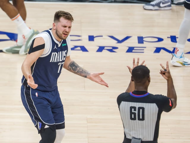 Basketballspieler streitet mit Schiedsrichter auf dem Spielfeld.