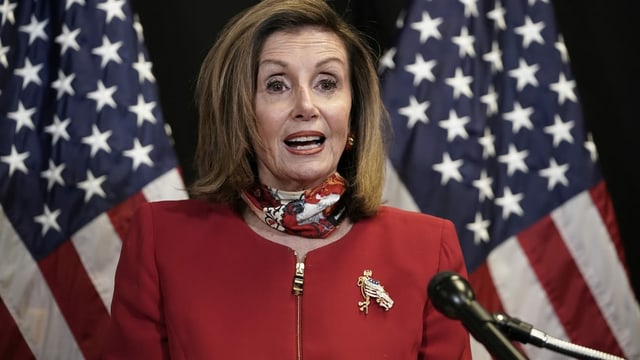 Nancy Pelosi in front of two American flags.