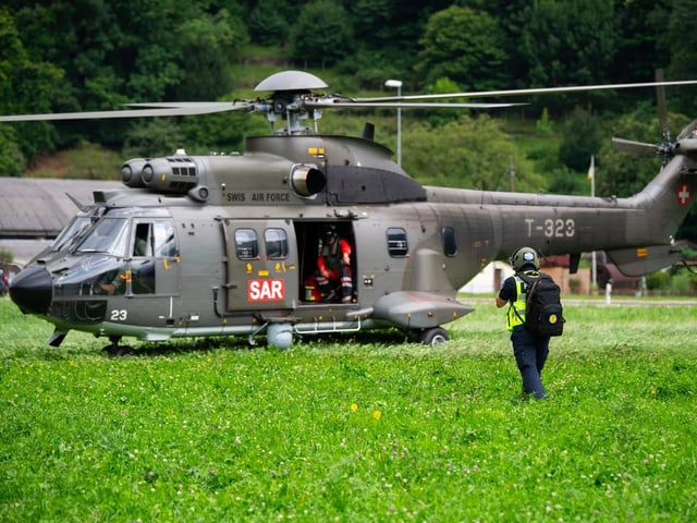 SAR-Hubschrauber auf einer Wiese, Person nähert sich.