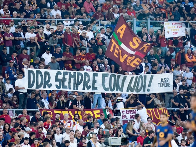 Fussballfans im Stadion halten Banner 'DDR SEMPRE CON NOI' hoch.