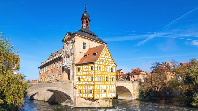 Eine altes Riegelhaus mit Türmchen als Teil einer Brücke mitten in einem Fluss. 