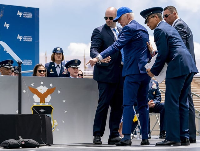 Biden zeigt auf den Sandsack, den ihn zum Stolpern brachte.