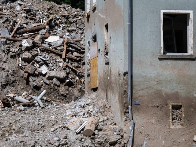 Teilweise zerstörtes Gebäude neben einem Schuttberg.