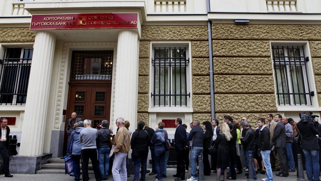 Leute warten vor der verschlossenen Türe einer Bank.